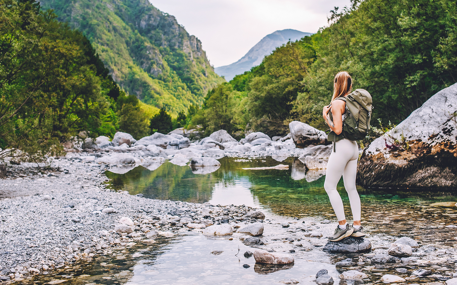 Woman hiking near Shala River in Tirana, surrounded by lush green mountains.