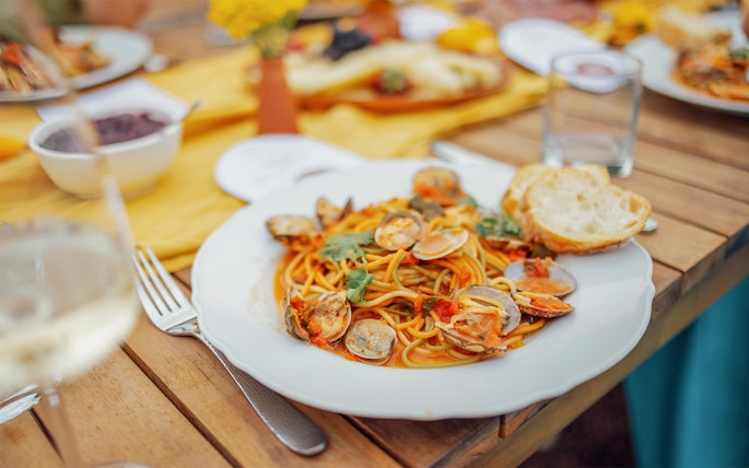 Seafood pasta dish on a wooden table during Cinque Terre tour from Florence.