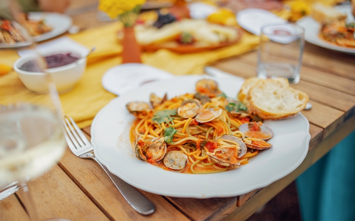 Seafood pasta dish on a wooden table during Cinque Terre tour from Florence.