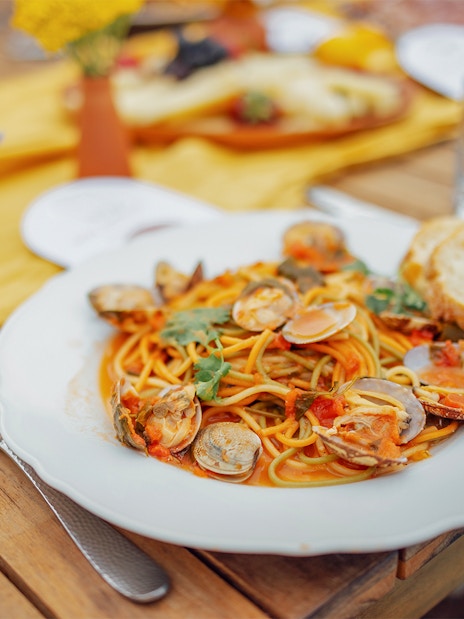Seafood pasta dish on a wooden table during Cinque Terre tour from Florence.