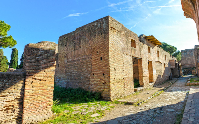 Ancient brick buildings and cobblestone path in Ostia Antica, Italy.