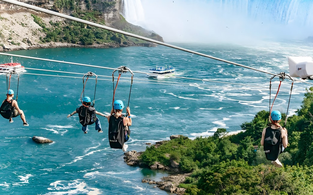Ziplining over river towards waterfall with boat below, Niagara Falls.