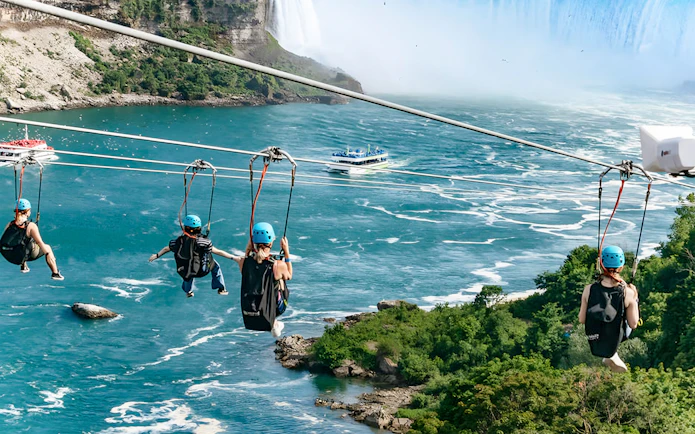 Ziplining over river towards waterfall with boat below, Niagara Falls.