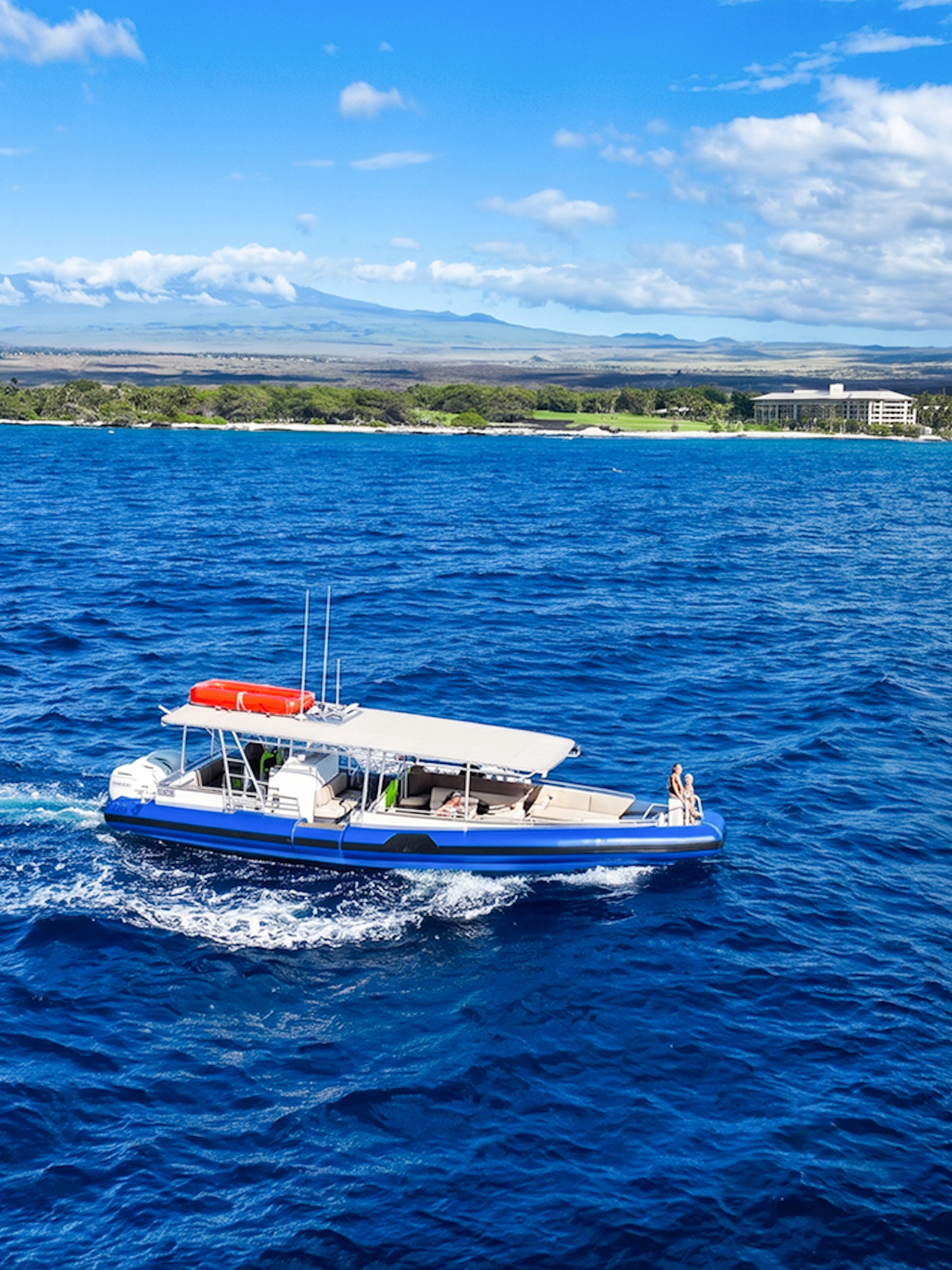Boat cruising along Big Island’s Kohala Coast with scenic shoreline in view.