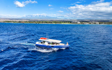 Boat cruising along Big Island’s Kohala Coast with scenic shoreline in view.