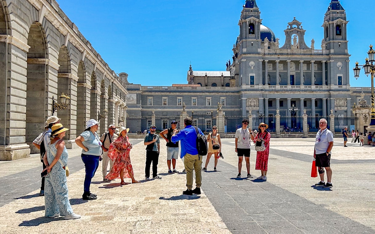 Tour guide with tourists outside the Royal Palace of Madrid.