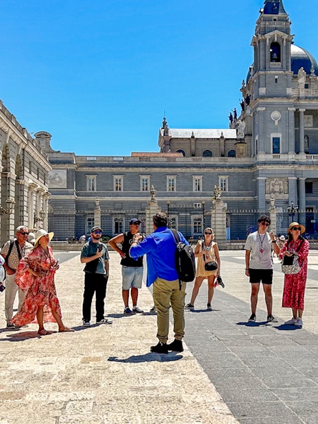Tour guide with tourists outside the Royal Palace of Madrid.