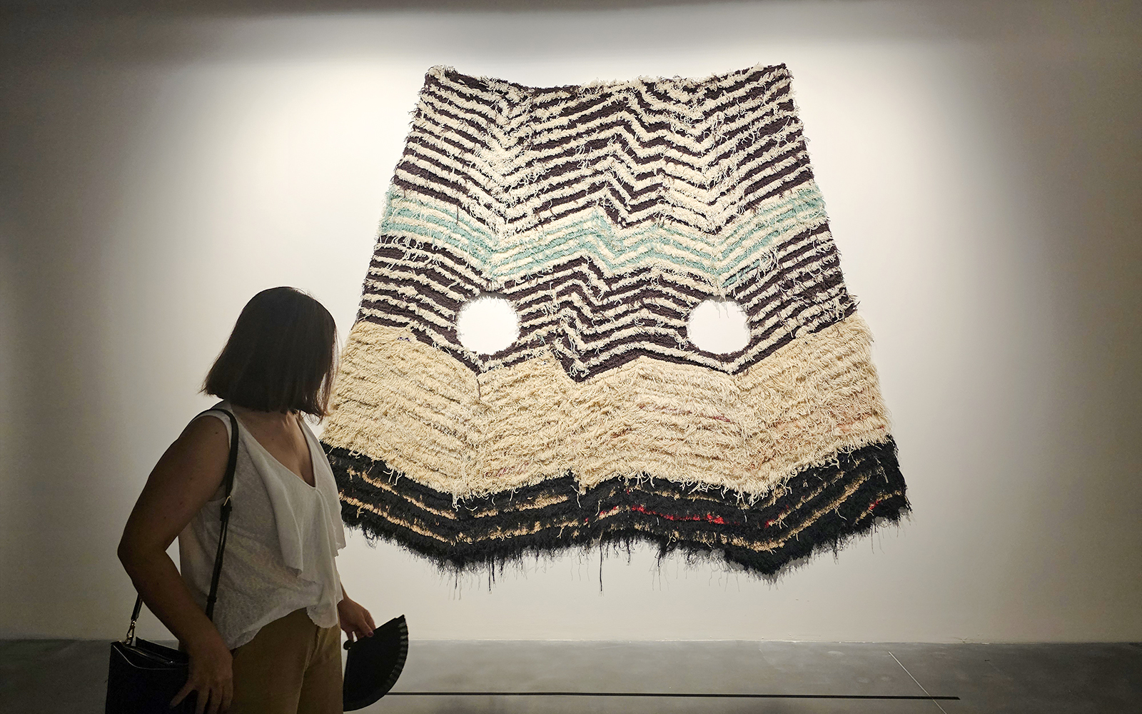 Visitor viewing textile art at Centre Pompidou Malaga exhibition interior.
