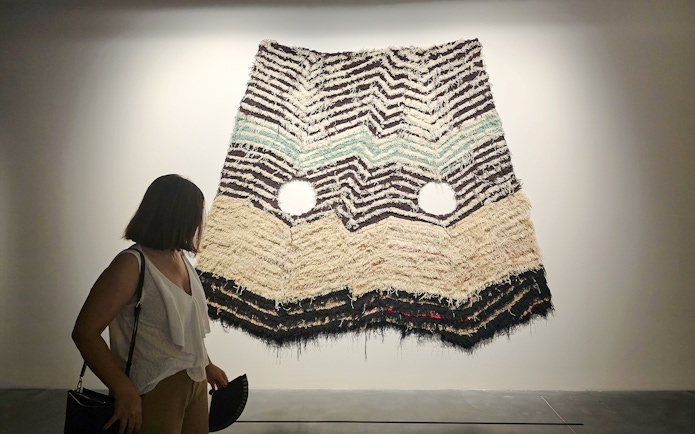 Visitor viewing textile art at Centre Pompidou Malaga exhibition interior.