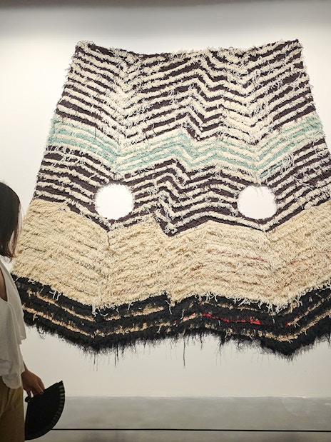 Visitor viewing textile art at Centre Pompidou Malaga exhibition interior.