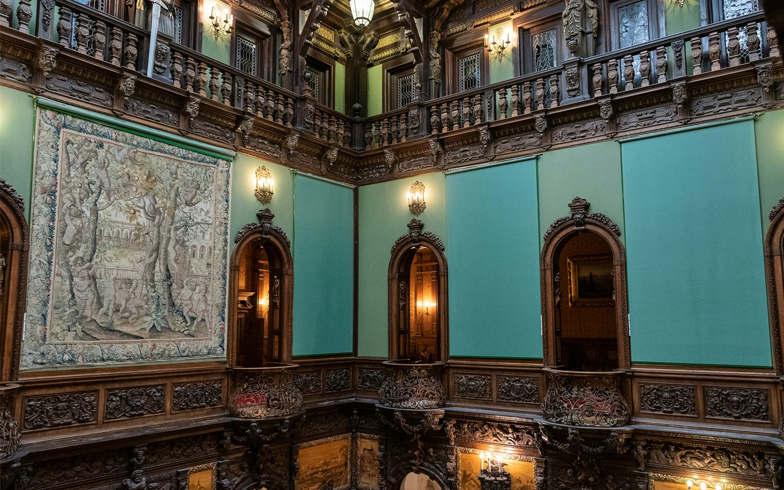 Hall of Honour in Peles Castle featuring ornate woodwork and a large tapestry.