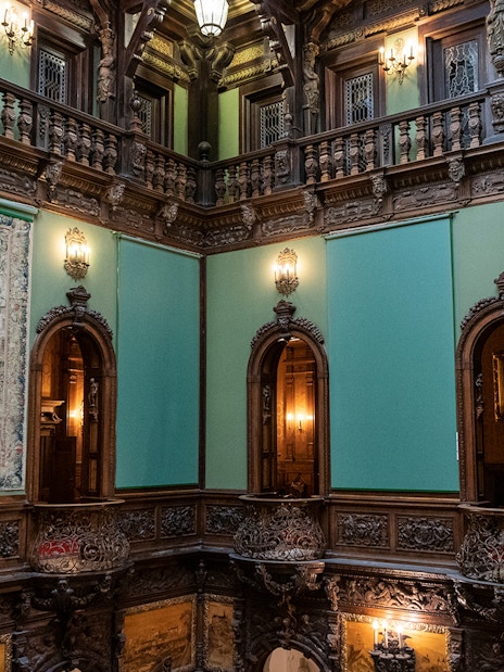 Hall of Honour in Peles Castle featuring ornate woodwork and a large tapestry.