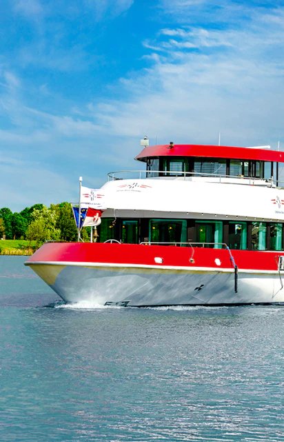 MS Vienna boat cruising on a river in Austria with lush green trees in the background.
