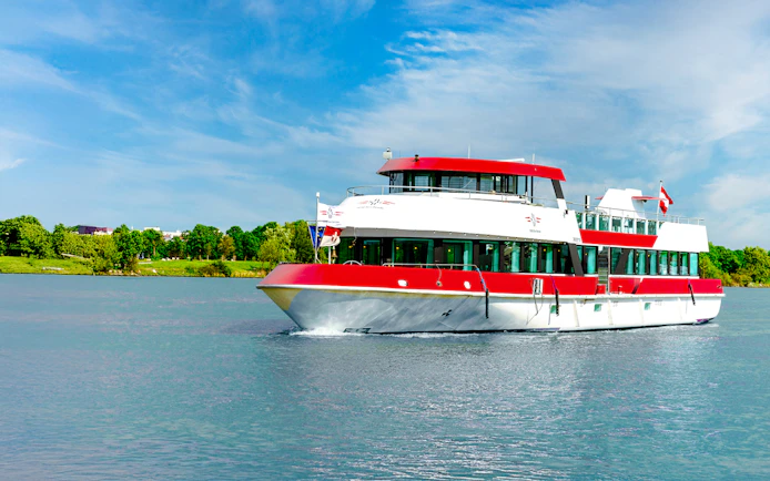 MS Vienna boat cruising on a river in Austria with lush green trees in the background.