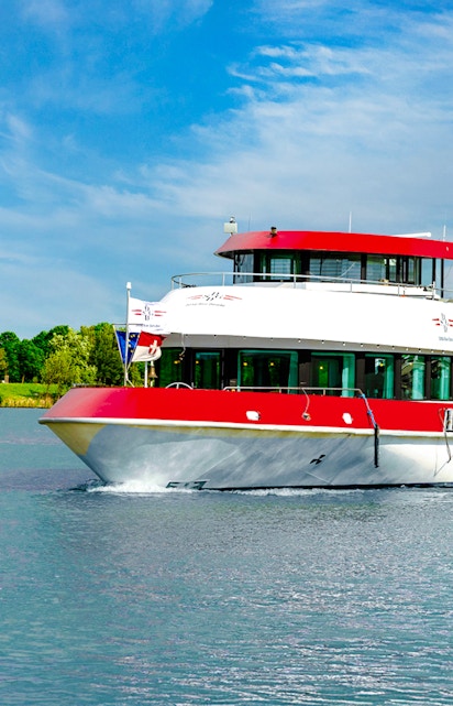 MS Vienna boat cruising on a river in Austria with lush green trees in the background.