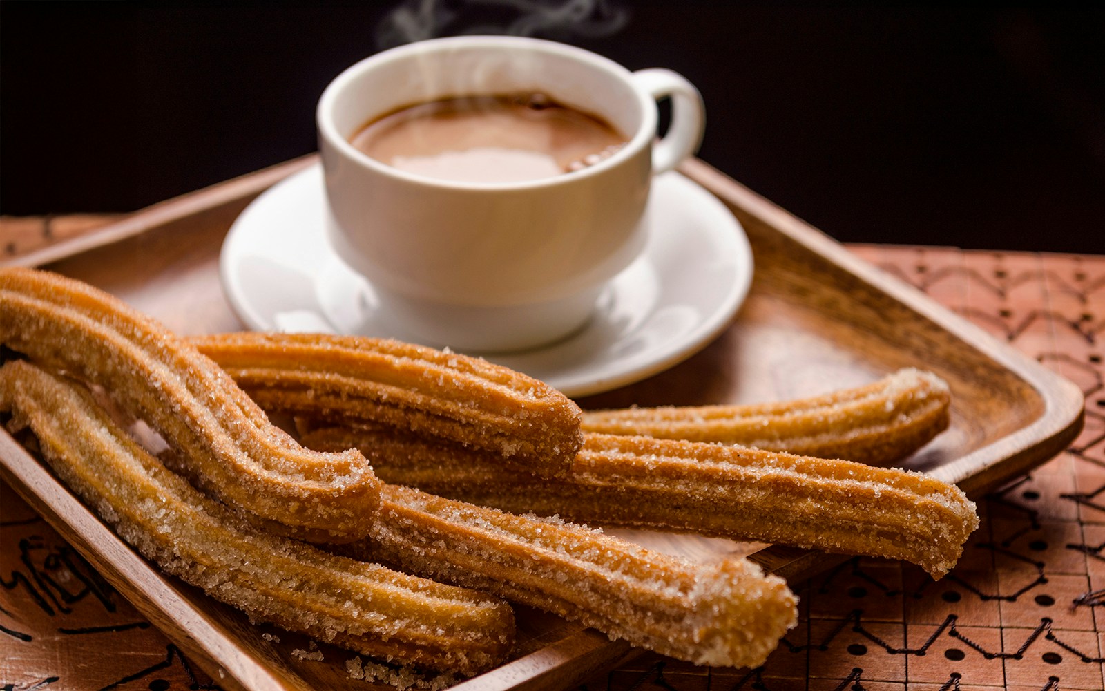 Churros con chocolate close-up, showcasing crispy churros dipped in rich chocolate sauce.