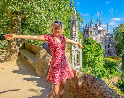 Visitor enjoying the view at Quinta da Regaleira, Sintra, with the palace in the background.