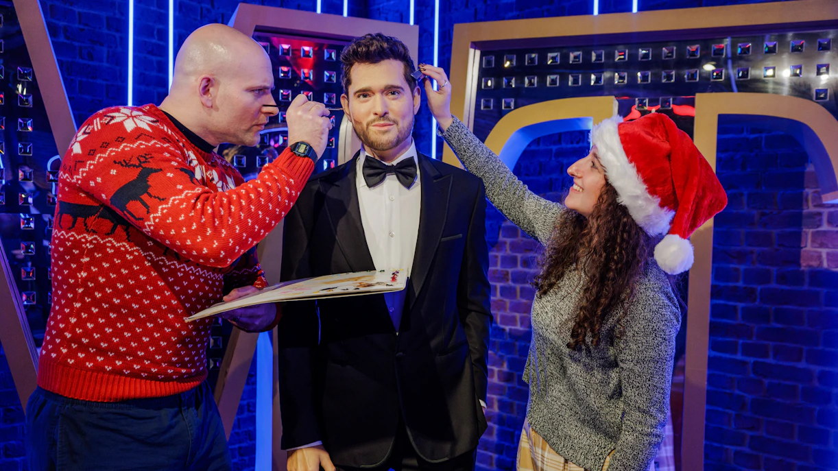 Wax figure of Michael Buble at Madame Tussauds during Christmas, with staff making adjustments.
