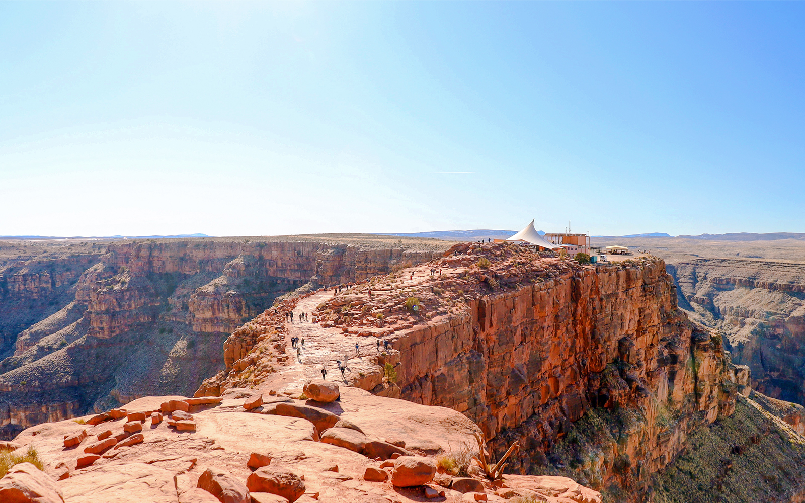 Grand Canyon West Rim with visitors walking along the cliff edge, seen from a helicopter tour.