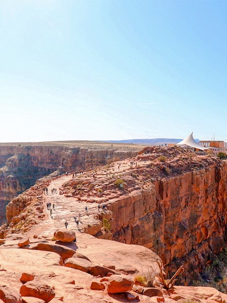 Grand Canyon West Rim with visitors walking along the cliff edge, seen from a helicopter tour.