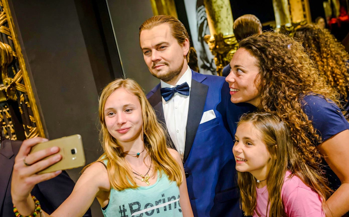 Visitors taking a selfie with a wax figure at Grévin Wax Museum, Paris.