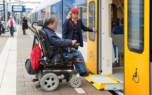 Wheelchair user boarding NS train at Schiphol Airport with assistance.