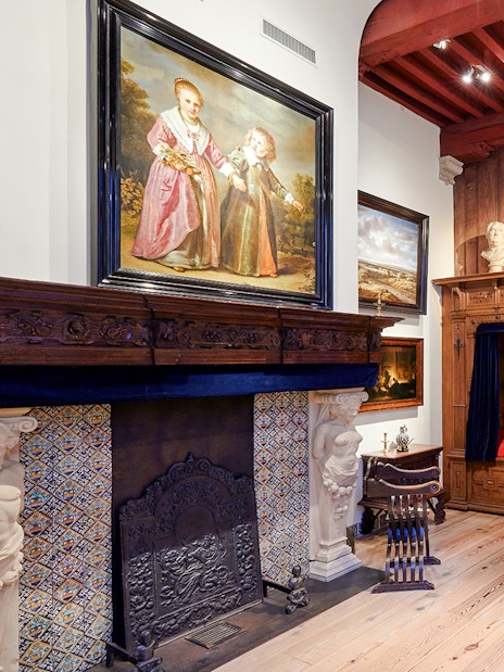 Interiors of the Rembrandt House Museum featuring a wooden bed, fireplace, and paintings.