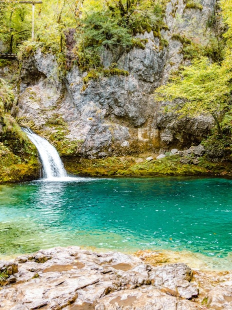 Waterfall flowing into Blue Eye spring surrounded by lush greenery in Gjirokaster.