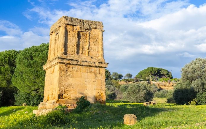 Ancient stone structure in Valley of the Temples, Sicily, surrounded by greenery.