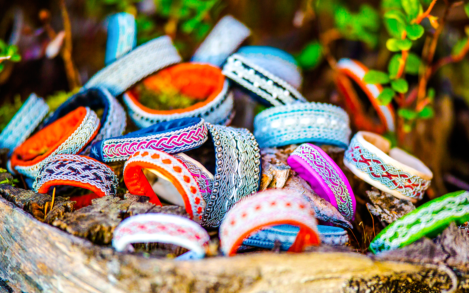 Sami tin wired bracelets in various colors displayed on wood.