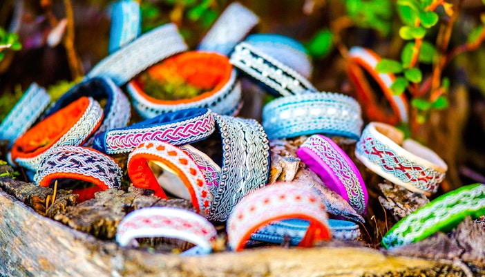 Sami tin wired bracelets in various colors displayed on wood.