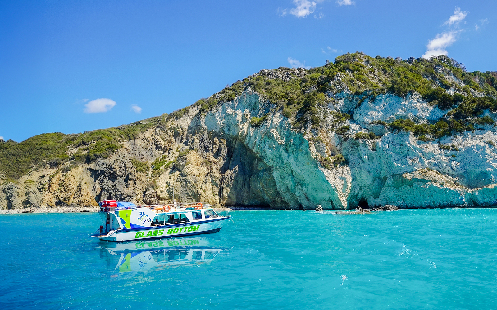 Glass bottom boat near rocky cliffs in Zakynthos, Greece.