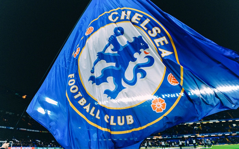 Chelsea FC flag waving at Stamford Bridge stadium during a night event.