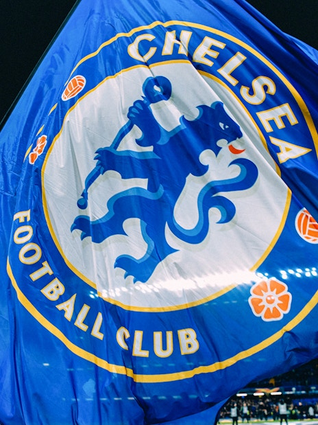 Chelsea FC flag waving at Stamford Bridge stadium during a night event.
