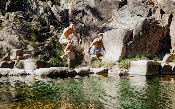 Jumping into a natural pool at Peneda Gerês National Park during a guided tour.