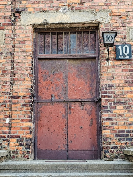 Barracks entrance at Auschwitz I, Block 10, with brick facade and metal door.