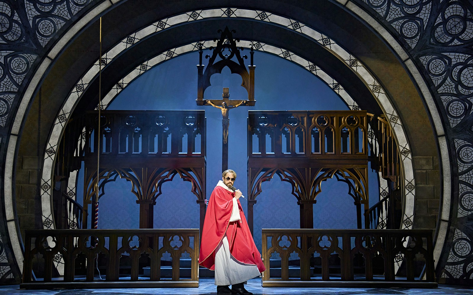Performer in red robe on stage set of Sister Act musical.