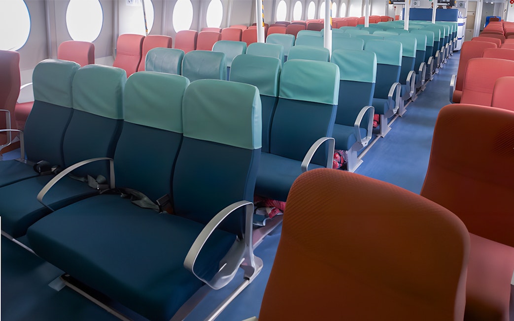 Ferry seating area with rows of blue and red seats at Tanah Merah Terminal.