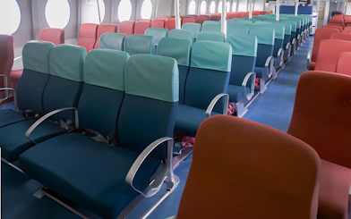 Ferry seating area with rows of blue and red seats at Tanah Merah Terminal.