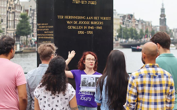 Group listening to a guide at a Jewish memorial in Amsterdam during a history tour.