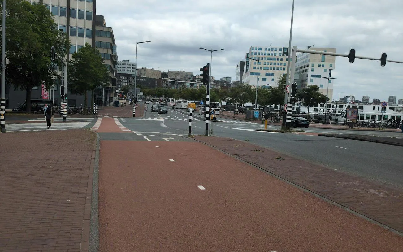 Amsterdam street view with bike lanes and modern buildings, part of the Ship-Sinking Secret exploration game.