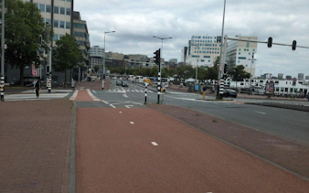 Amsterdam street view with bike lanes and modern buildings, part of the Ship-Sinking Secret exploration game.