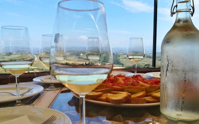 Wine glasses and bruschetta on a table overlooking Tuscan vineyards during a private tour from Florence.