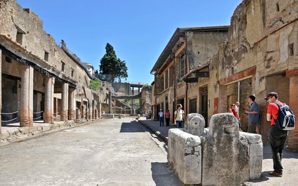 Herculaneum ruins with tourists exploring ancient streets on a guided tour from Naples.