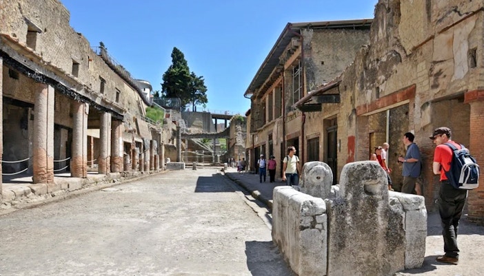 Herculaneum ruins with tourists exploring ancient streets on a guided tour from Naples.