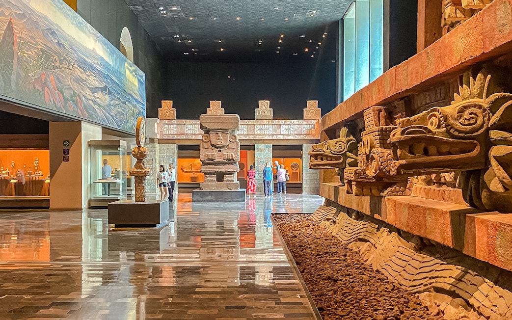 Ancient stone sculptures and visitors inside the Anthropology Museum, Mexico.