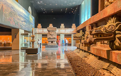 Ancient stone sculptures and visitors inside the Anthropology Museum, Mexico.