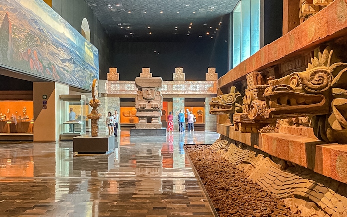 Ancient stone sculptures and visitors inside the Anthropology Museum, Mexico.