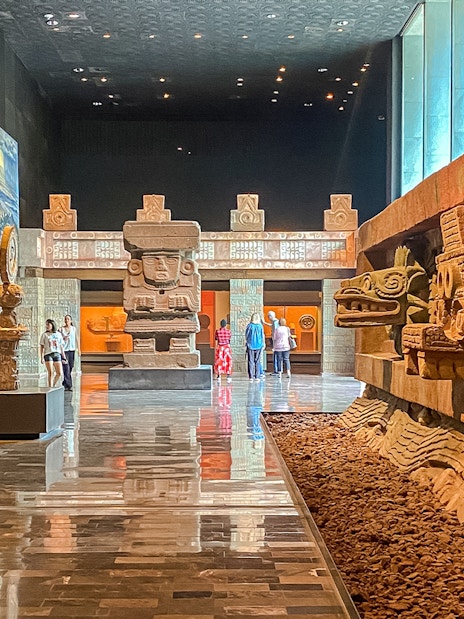 Ancient stone sculptures and visitors inside the Anthropology Museum, Mexico.