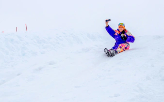 Person sledding on snowy slope at Valle Nevado, Santiago.
